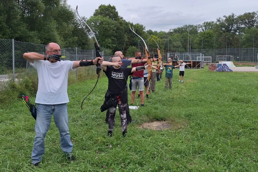 Bogenschießen als Teamevent - Eine Gruppe von Menschen beim Syncronschießen mit gespanntem Bogen